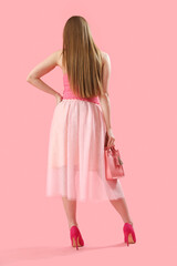 Fashionable young woman on pink background, back view