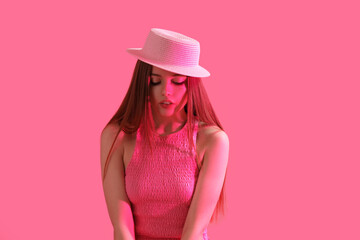 Fashionable young woman in hat on pink background