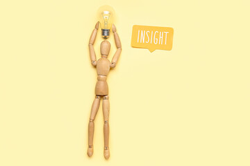 Wooden mannequin with light bulb and word INSIGHT on beige background
