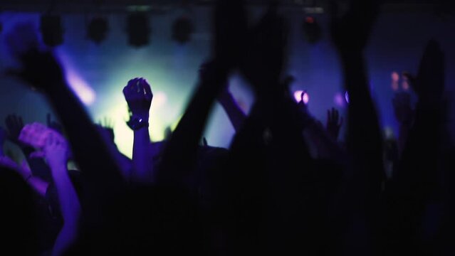 Concert crowd waving hands in the club. People party with music and enjoy amazing show on the stage. Video is in slow motion.