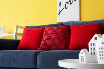 Red pillows on blue sofa in living room, closeup