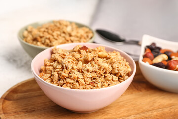 Bowls of tasty granola on light background, closeup