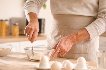 Male chef making dough for pasta at table in kitchen, closeup