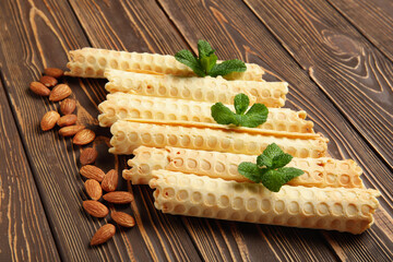 Delicious wafer rolls with almond nuts and mint on brown wooden background