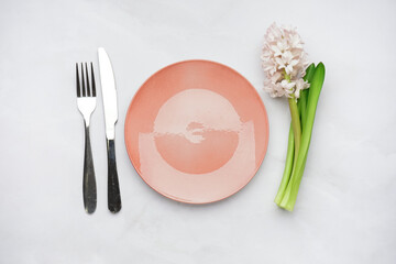 Clean plate, cutlery and beautiful hyacinth flower on white background