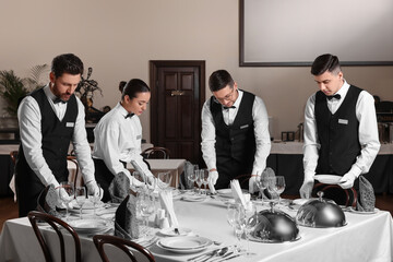 People setting table during professional butler courses in restaurant