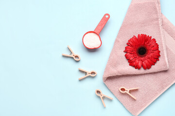 Laundry detergent, clothespins and gerbera flower on blue background