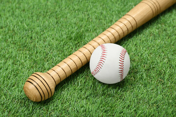 Wooden baseball bat and ball on green grass. Sports equipment