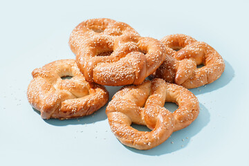 Tasty pretzels with sesame seeds on color background