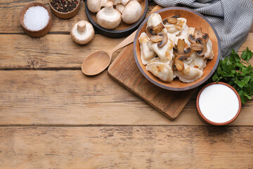 Delicious dumplings (varenyky) with potatoes, onion and mushrooms served on wooden table, flat lay. Space for text
