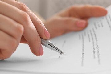 Woman signing document with pen, closeup view