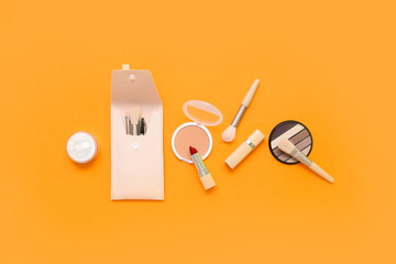Decorative cosmetics with makeup brushes on orange background