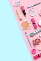 Decorative cosmetics with makeup brushes on blue and pink background