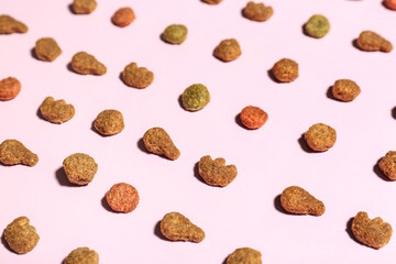Composition with dry pet food on pink background, closeup
