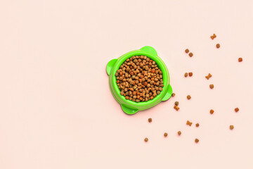 Bowl of dry pet food on pink background