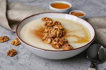 Bowl of tasty semolina porridge with nuts, cinnamon and honey on grunge background