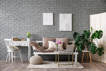 Interior of stylish living room with sofa, modern laptop and flower vase on coffee table