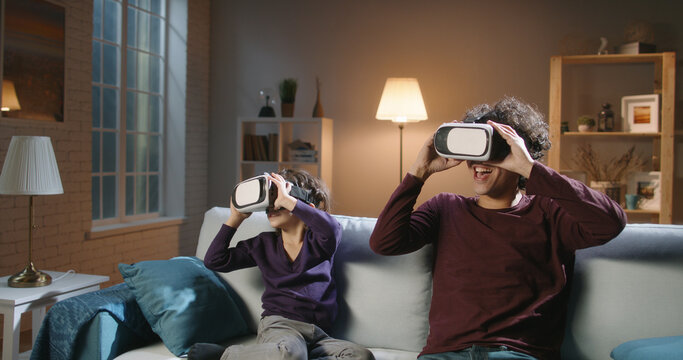 Funny south asian siblings or father and son with curly hair are trying virtual reality headsets, having fun playing video games - modern technologies, family time concept 