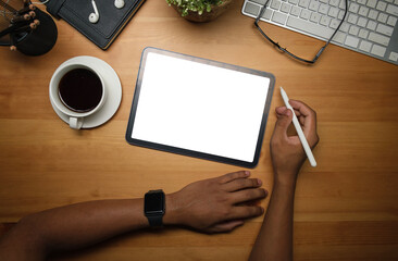 Overhead shot of man hand holding stylus pen, using digtal tablet on wooden working desk.