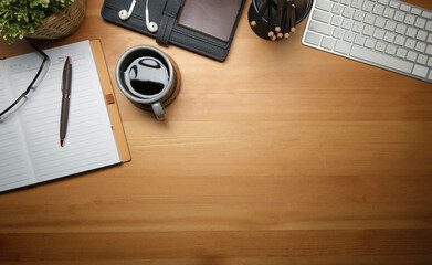 Flat lay, top view wooden office  desk with notebook, coffee cup and supplies. Copy space for text.