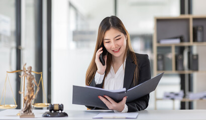 Attractive young lawyer in office Business woman and lawyers discussing contract papers with brass scale on wooden desk in office. Law, legal services, advice, Justice and real estate concept.