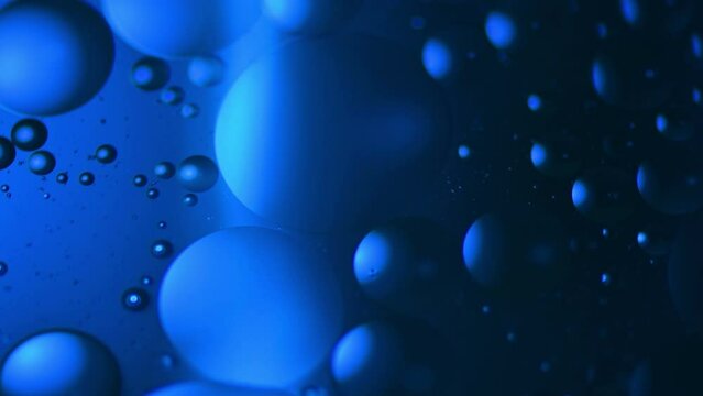 Swirling bubbles of oil in water shot through blue colored jell.