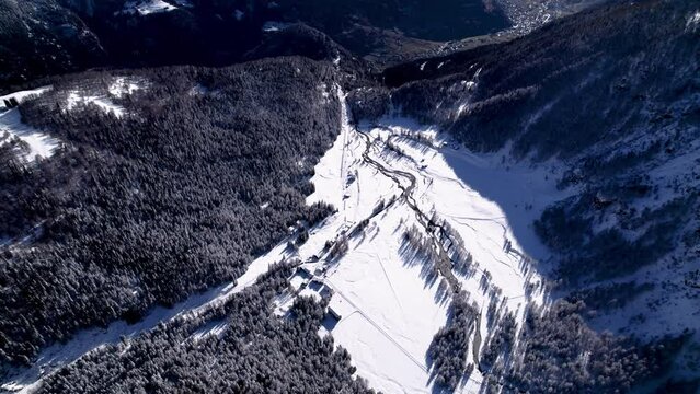 Aerial view of snow covered  landscape with forestsm hills and rivers on a sunny winter day in Alp Grum, Switzerland.