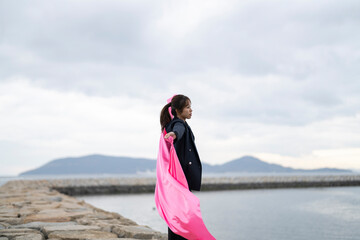 海でピンクの布を持った女性