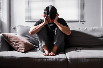 Close up of asian man with depression sitting alone on sofa