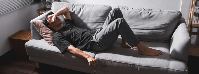 Stressed man lying on sofa holding glasses for relax. For banner design - obrazy, fototapety, plakaty