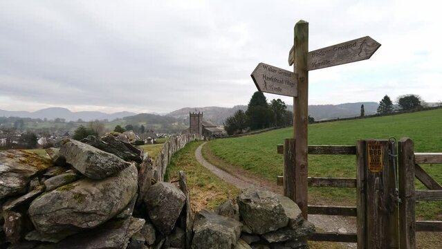 Wooden trail sign where the nature path splits into two. Showing church and farmland in the distance.