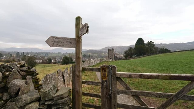 Wooden trail sign where the nature path splits into two. Showing church and farmland in the distance.
