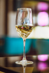 A glas of white wine in front of a blurred background of an urban street.