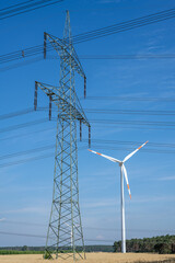Electricity pylon, wind turbine and power cables seen in Germany - 584529233