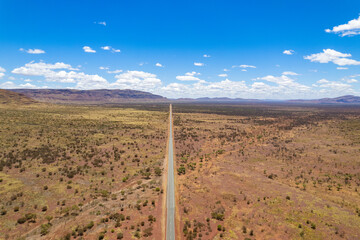 Aerial view of remote asphalt road surrounded by dry arid land in the Australian outback