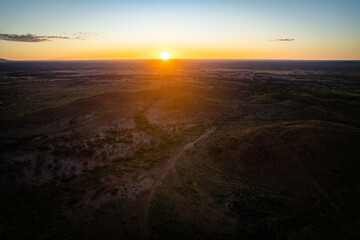 Looking down at a remote mountainous landscape as the sun rises over the horizon
