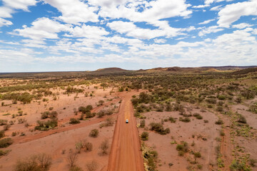4WD car driving down a dusty red earth road in outback Australia