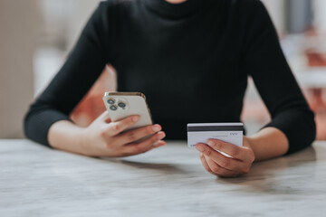 online payment Young woman's hand holding a credit card and using a smartphone for online shopping.