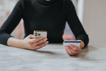 online payment Young woman's hand holding a credit card and using a smartphone for online shopping.