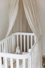 Soft sheep toy on beige cocoon, baby nest for newborn over cribs in nursery. Childhood concept....