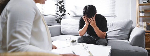 Psychologist sitting and touch hand young depressed asian man for encouragement, PTSD Mental health concept, For banner design