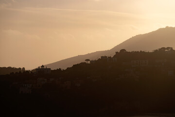 Houses of Procida in magic sunset with the island of Ischia in the background.
