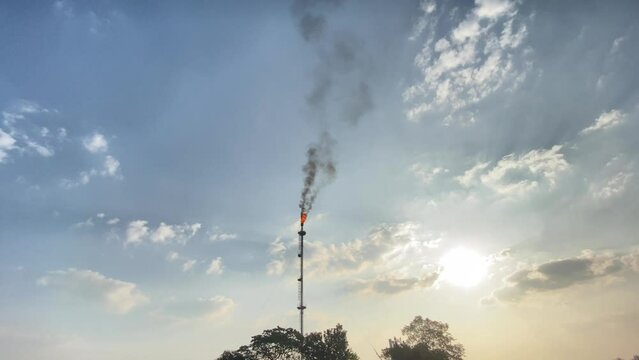 Establisher wide view of single burning Flare stack flame releasing Co2
