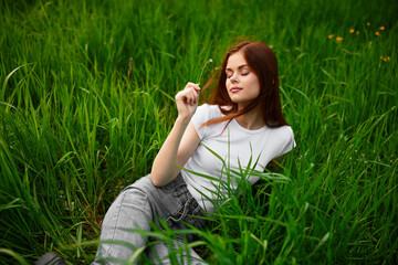 woman in gray jeans resting lying in the grass