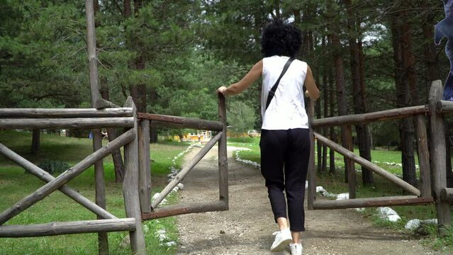Woman walk throuygh ranch farm barn fence wooden doors