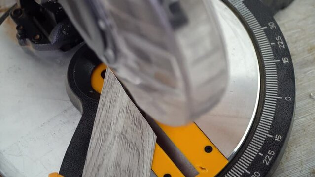 Man with a chop saw cuts laminate batten on a construction site. Lay parquet floor.