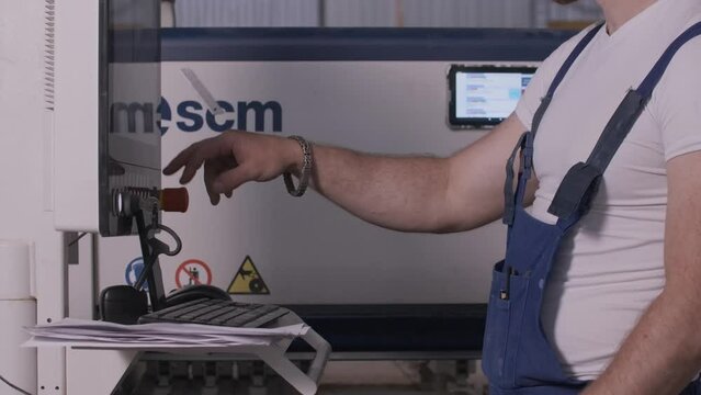 Man clicks on control panel of factory. Creative. Man in uniform adjusts panel at factory. Factory equipment control panel