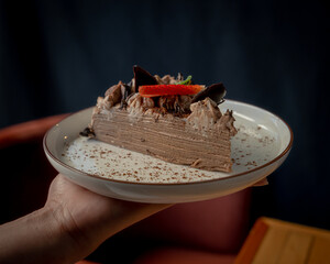 Delicious and exquisite slice of crepe cake with chocolate and strawberries on top.