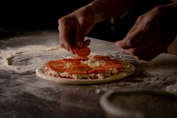 Cheef preparing a peperonni pizza in a kitchen.