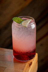 Fresh Strawberry Italian Soda topped with cut strawberry and rosemary leaves in a drinking glass with white straw.